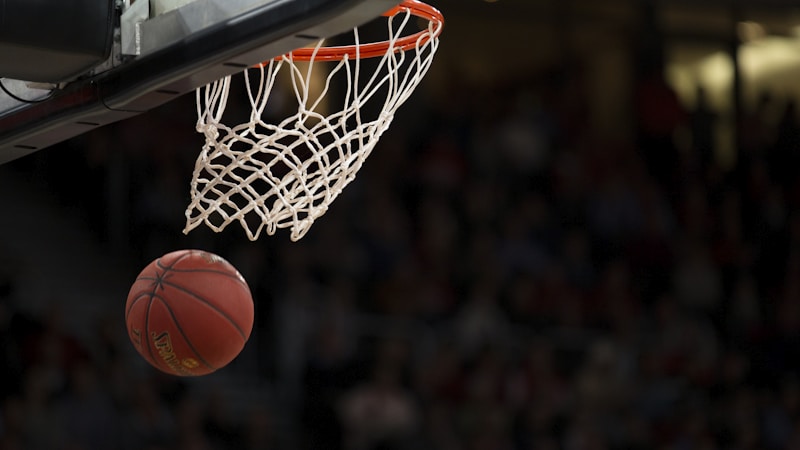 NBA常规赛精彩瞬间，篮球运动员腾空上篮，场馆内灯光聚焦赛场